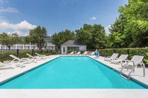 a swimming pool with chaise lounges and chairs at Baymont by Wyndham Anderson Clemson in Anderson