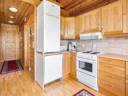 a kitchen with white appliances and wooden cabinets at 6 person holiday home in Ånneland in Ånneland