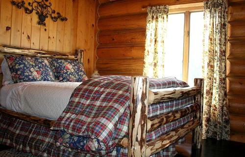 une chambre avec un lit dans une cabane en rondins dans l'établissement Luxury Cabin with a Hot Tub near Yellowstone Park in Montana, à Nye