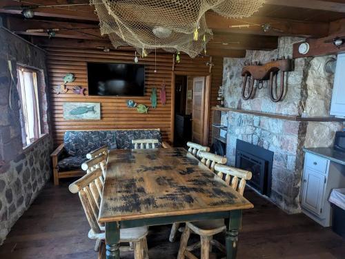 comedor con mesa de madera y chimenea en Rustic Two-Story Cabin Rental with Lake Access in Hayward, Wisconsin, en New Post