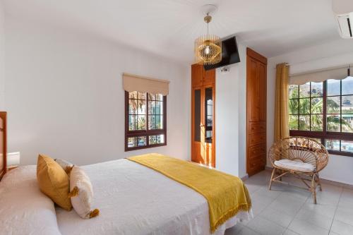 Un dormitorio con una cama y una silla y ventanas. en Orion Beach, en Puerto