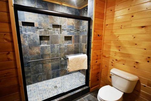 a bathroom with a toilet and a glass shower at Rustic Fishing Lodge Rental with a Spacious Deck in Logan, Ohio in Cedar Grove