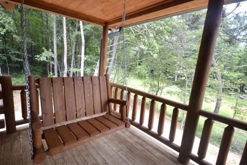 a porch of a cabin with a porch swing at Rustic Fishing Lodge Rental with a Spacious Deck in Logan, Ohio in Cedar Grove