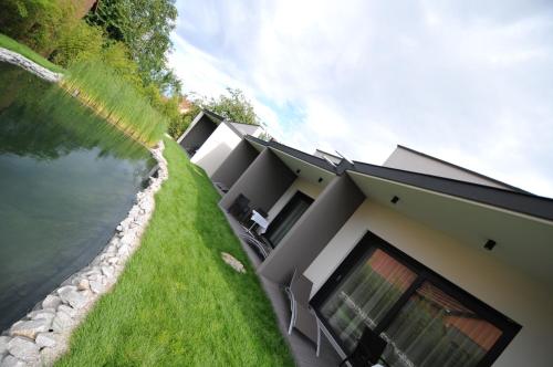 a house with a retaining wall next to a body of water at Logis Hotel Restaurant Au Boeuf Rouge in Niederschaeffolsheim