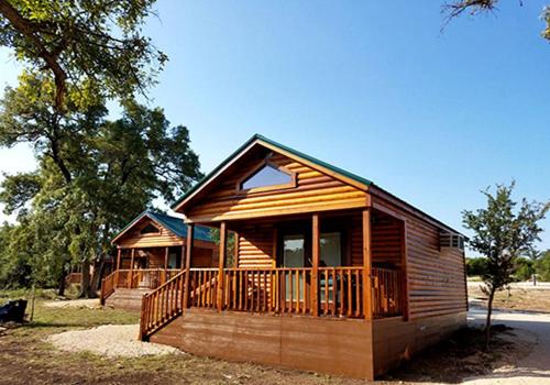 a log cabin with a porch and a deck at Amazing Family Vacations in Nature in this Cute Log Cabin near Austin, Texas in Pipe Creek