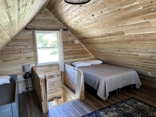 a room with a bed in a wooden cabin at Magnificent Cabin Nestled Amidst Trees in Portage Lake, Maine in Portage Lake Municipal Seaplane Base