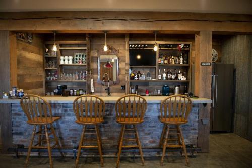 a bar with four wooden bar stools at a counter at Charming Historic-Inspired Vacation Home with Mountain Views near Pony School House in Pony, Montana in Pony