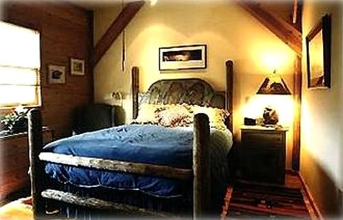 a bedroom with a bed with a blue comforter at Remote Six-Bedroom Lodge for Rent near the Chico Hot Springs, Montana in Flying Y Ranch Airport