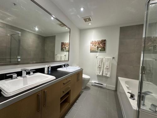 Modern 3-Bedroom Apartment in UBC في فانكوفر: حمام مع مغسلتين ومرحاض ودش