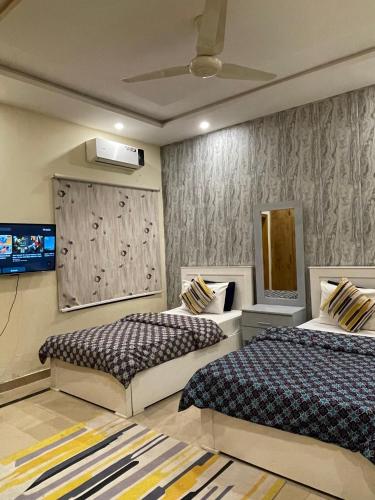 a bedroom with two beds and a tv on the wall at Dream Lodge House in Islamabad