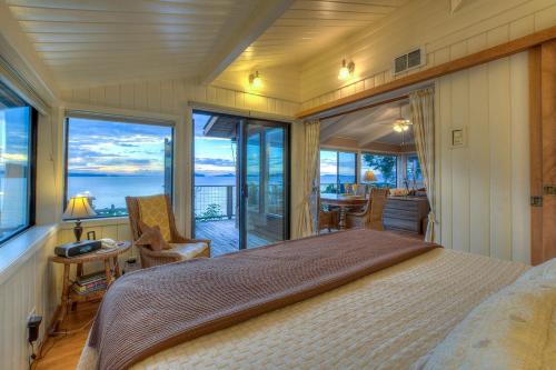 une chambre avec un grand lit et de grandes fenêtres dans l'établissement Waterfront Cottage Rental with Spectacular Sunset Views on Orcas Island, Washington, à Deer Harbor