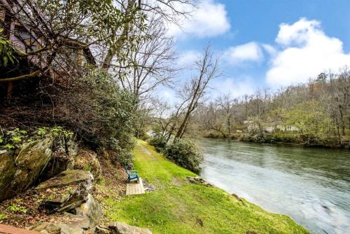 a bench sitting on the side of a river at Romantic Riverfront Cabin with Pool Access in Blue Ridge, Georgia in Mineral Bluff