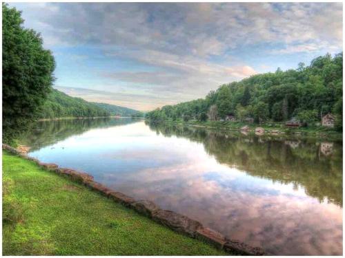 a river with trees on the side of it at Scenic Retreat: Riverfront Cabin with Large Deck and Fire Pit in Emlenton, Pennsylvania in Emlenton