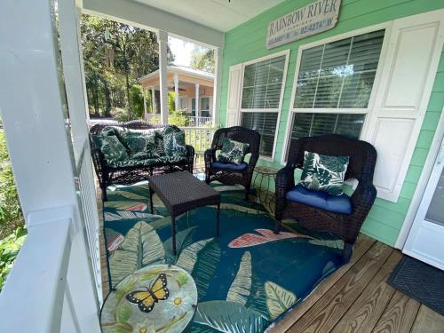 a porch with three chairs and a table on a house at Charming Cottage Surrounded by Trees in Dunnellon, Florida in Dunnellon