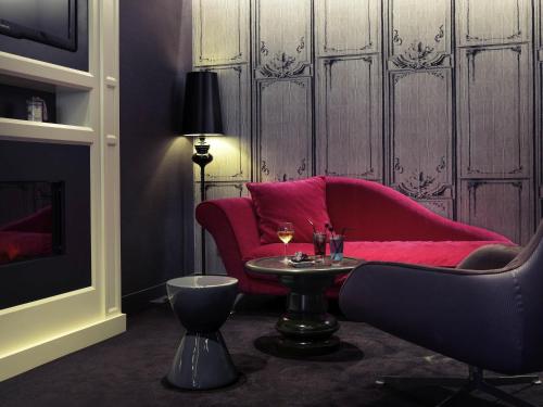 a living room with a red couch and a table at Mercure Toulouse Centre Wilson Capitole in Toulouse