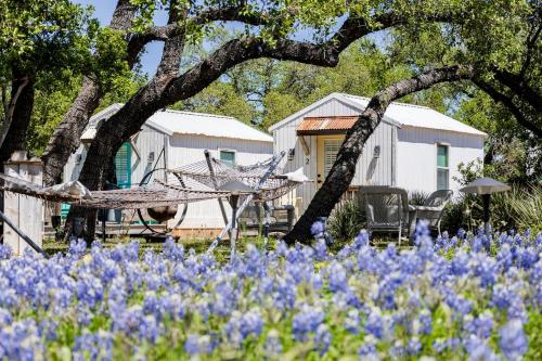 a garden with blue flowers in front of a house at Newly Renovated Camper with Fresh Decor and Tiny Deck in Texas in Spicewood