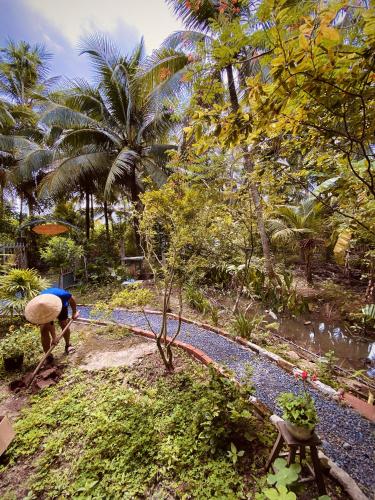 a person working in a garden with a tree at Bến Tre Homestay in Ben Tre