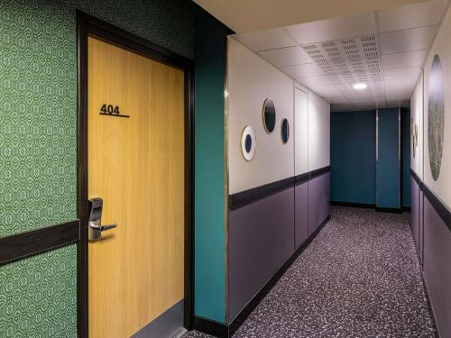 an office hallway with a door and green and blue walls at Mercure Mulhouse Centre in Mulhouse