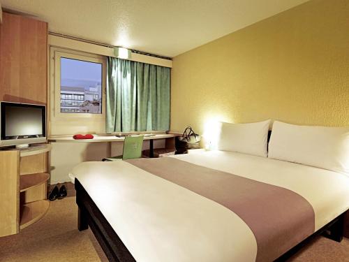 a hotel room with a large bed and a television at Hotel ibis Setubal in Setúbal