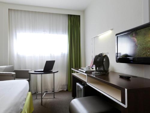 a hotel room with a bed and a flat screen tv at Mercure Rennes Centre Gare in Rennes
