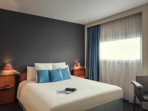 a bedroom with a large bed with blue pillows at Mercure Rennes Centre Gare in Rennes