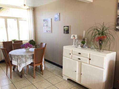 a dining room with a table and a white dresser at Gîte Margot in Vacqueriette