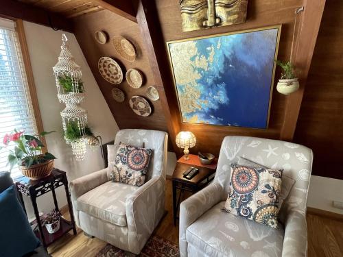 a living room with two chairs and a painting on the wall at Gorgeous A-Frame by the Beach in Otter Rock, Oregon in Otter Rock