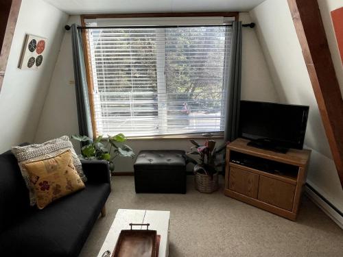 a living room with a black couch and a television at Gorgeous A-Frame by the Beach in Otter Rock, Oregon in Otter Rock