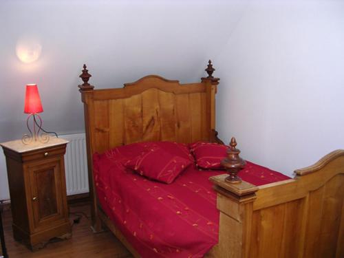 a bedroom with a wooden bed with red sheets at Gîte Margot in Vacqueriette