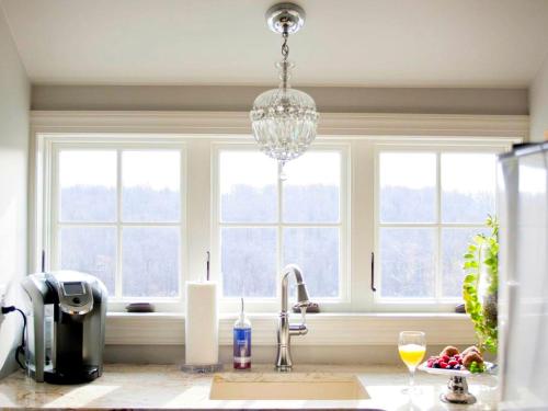 a kitchen with a sink and a chandelier in front of windows at Stylish Cottage Loft Rental on a Farm in Lancaster County near Philadelphia, Pennsylvania in Christiana