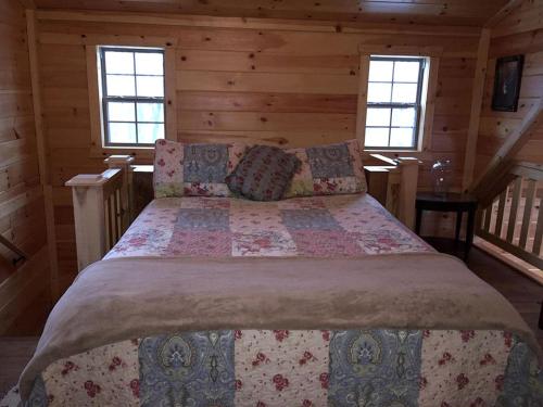 Ce lit se trouve dans une cabane en rondins dotée de 2 fenêtres. dans l'établissement Cozy Family-Friendly Cabin with Private Outdoor Jacuzzi near Huntington, West Virginia, à Genoa