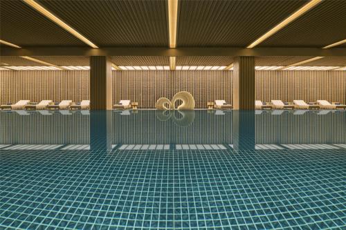 a swimming pool with toilets and chairs in a building at Shu Hua Hotel Tianmu Mountain, Curio Collection By Hilton in Hangzhou