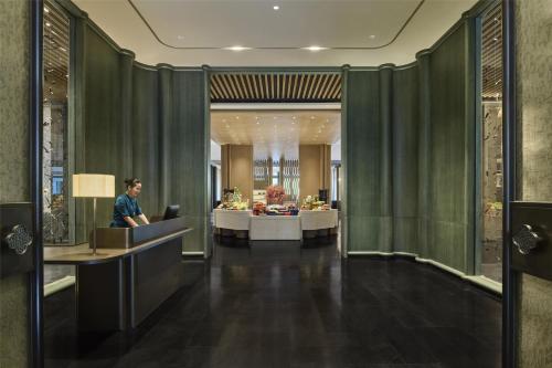 a man sitting at a desk in a hotel lobby at Shu Hua Hotel Tianmu Mountain, Curio Collection By Hilton in Hangzhou