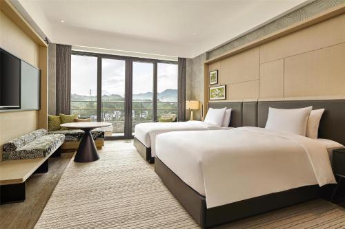 two beds in a hotel room with a television at Shu Hua Hotel Tianmu Mountain, Curio Collection By Hilton in Hangzhou
