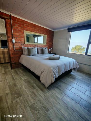 a bedroom with a large bed with a brick wall at Oppi Plaas See Uitsig Seemeeu in Great Brak River