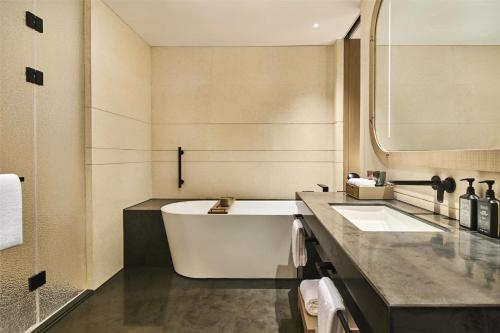 a bathroom with a large tub and a sink at Shu Hua Hotel Tianmu Mountain, Curio Collection By Hilton in Hangzhou