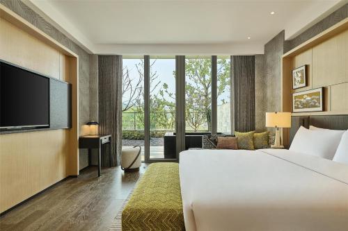 a hotel room with a large bed and a flat screen tv at Shu Hua Hotel Tianmu Mountain, Curio Collection By Hilton in Hangzhou
