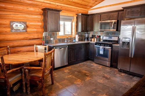 a kitchen with wooden cabinets and a wooden table in a cabin at Cozy 1-Bedroom Log Cabin with Full Kitchen & Wi-Fi | Bonners Ferry, Idaho Retreat in Bonners Ferry