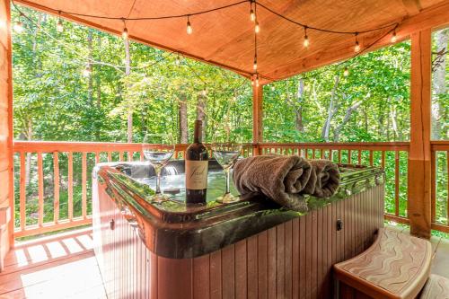 a wooden deck with a table with wine bottles and glasses at Relaxing Cabin with Screened Porch in Sautee Nacoochee, Georgia in Sautee Nacoochee