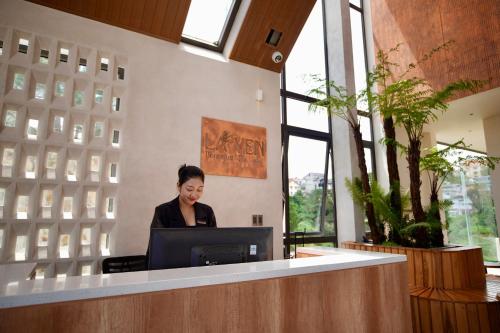 a woman sitting at a desk with a computer at Là Yên Villa - Đà Lạt in Ấp Ða Lợi