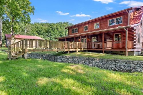 a log home with a deck and a stone wall at Stunning Cabin with Hot-tub, Fire Pit and Games in Stanton, Kentucky in Stanton