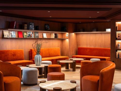 a waiting room with orange chairs and tables at Mercure Rouen Centre Champ de Mars in Rouen