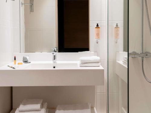 a white bathroom with a sink and a mirror at Mercure Rouen Centre Champ de Mars in Rouen