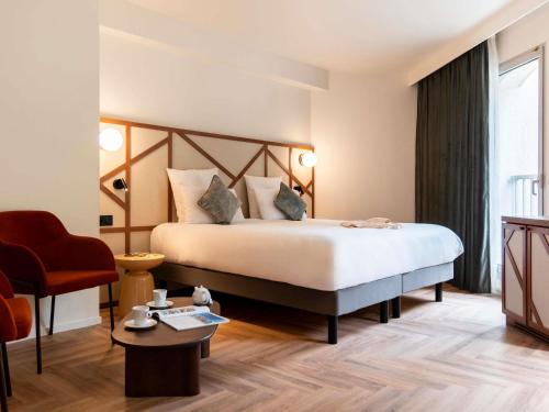 a hotel room with a bed and a chair at Mercure Rouen Centre Champ de Mars in Rouen