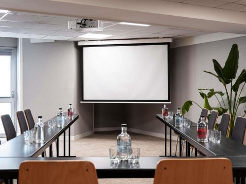 a conference room with tables and chairs and a screen at Mercure Rouen Centre Champ de Mars in Rouen