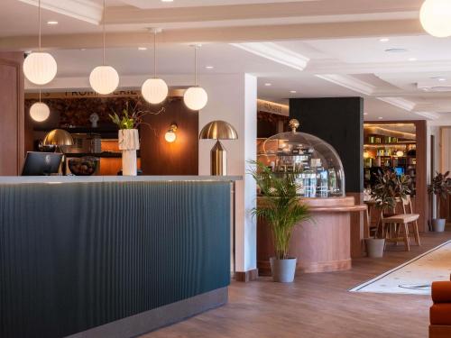 a bar in a restaurant with potted plants and lights at Mercure Rouen Centre Champ de Mars in Rouen