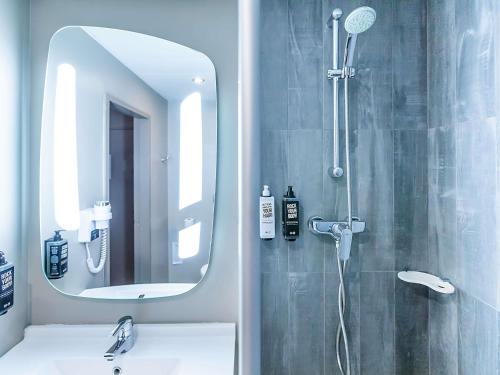a bathroom with a shower with a sink and a mirror at Hotel ibis Porto Gaia in Vila Nova de Gaia