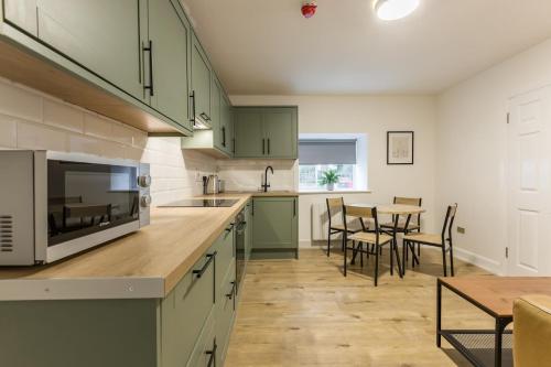 eine Küche mit grünen Schränken und einem Tisch mit Stühlen in der Unterkunft Contractor's Cottage Kildare 5 Double Beds in Bodenstown