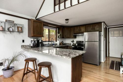 a kitchen with a counter and two bar stools at Enchanting A-Frame Cabin Retreat near Berkeley Springs and Mountain Views in West Virginia in Baxter