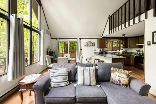 a living room with a blue couch and a kitchen at Enchanting A-Frame Cabin Retreat near Berkeley Springs and Mountain Views in West Virginia in Baxter